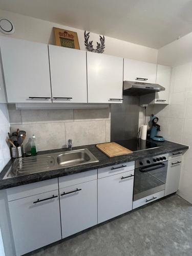 a kitchen with white cabinets and a sink at Le Panorama - GÎTES MARCK in Turckheim