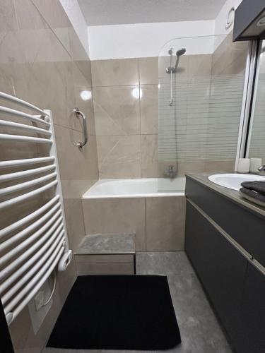 a bathroom with a bath tub and a sink at Le Panorama - GÎTES MARCK in Turckheim