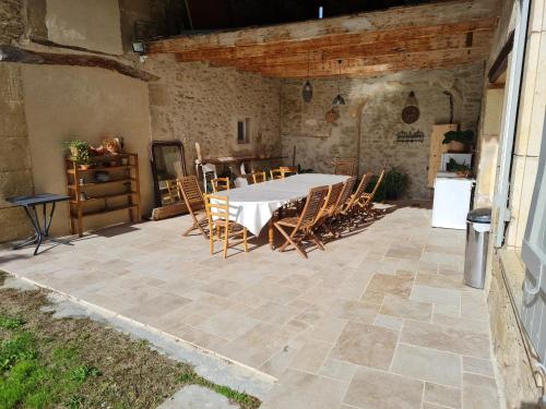 un patio avec une table et des chaises dans un bâtiment dans l'établissement Le Sabatin - Maison de charme, un écrin de verdure, à Upie