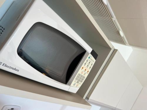 a microwave oven sitting on top of a shelf at Refúgio do Mar 703 - Condomínio Edifício Ritz Suítes Home Service in Maceió