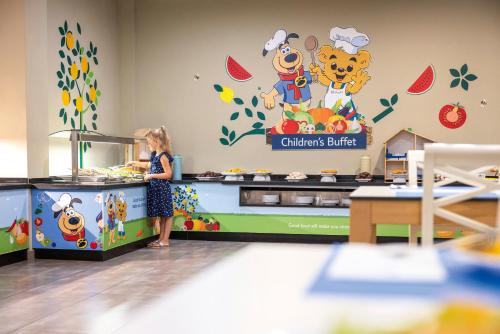 a young girl is preparing food at a buffet at Grupotel Alcudia Pins in Playa de Muro
