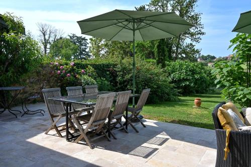 a table and chairs with an umbrella on a patio at La Petite Toscane en Beaujolais in Saint-Vérand
