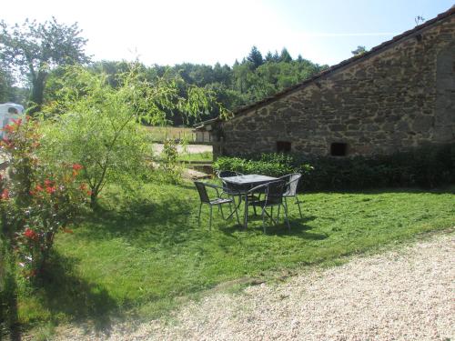 a table and chairs in a yard next to a stone building at Ecuries de Saint Maurice- Maison d'hôtes de Gondou in Lacapelle-Marival