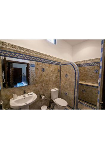 a bathroom with a sink and a toilet and a mirror at Riad Fes Ziyat & Spa in Fès