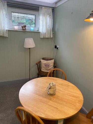 a wooden table with chairs and a lamp in a room at Rose Cottage in Wigton
