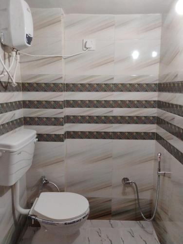 a toilet in a bathroom with stripes on the wall at Geeta Teerth Guest House AC and Non AC Rooms in Ayodhya