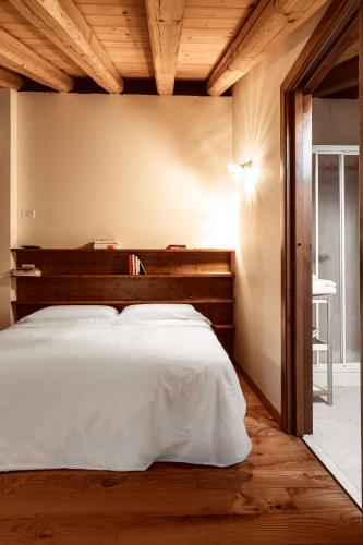 a bedroom with a large bed with a wooden headboard at Asolo Norah's Hill Agri Rooms in Caenere