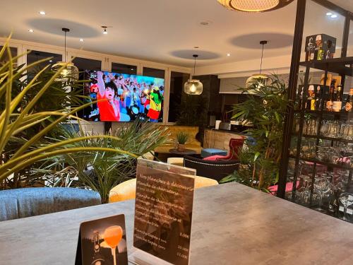 a bar with a tv in a room with plants at Le Clos Joli in Haybes