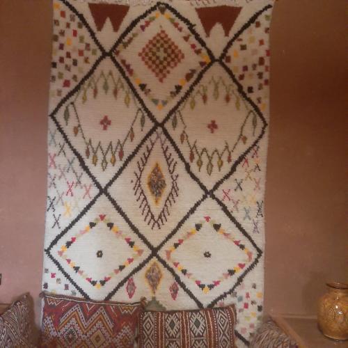 a quilt hanging on a wall with pillows at Maison d'Hôte Valentine in Tinerhir