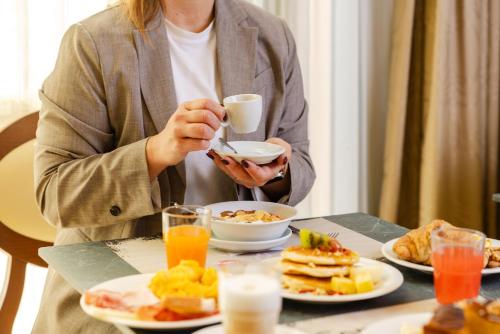 a woman sitting at a table with a plate of breakfast food at Il Gentiluomo Hotel & SPA in Arezzo
