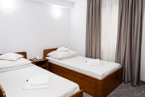 a hotel room with two beds and a window at Hotel Casa de Piatra in Scheia