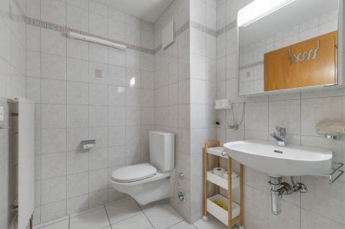a white bathroom with a toilet and a sink at Nid douillet aux bains de Saillon in Saillon