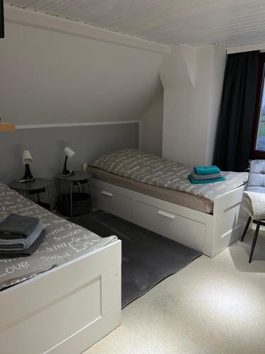 a white bedroom with a bed and a chair at Pension Küstenkind in Bentwisch