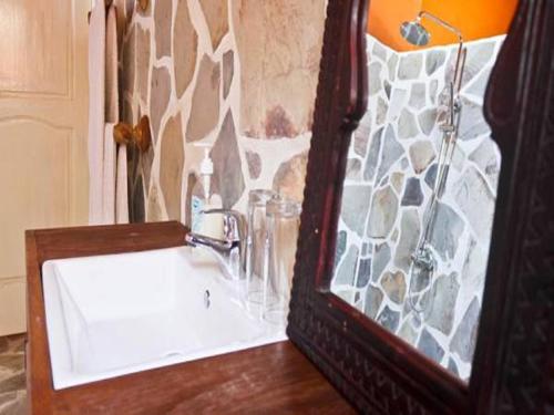 a bathroom with a white sink and a stone wall at Pure Plage in Lomé