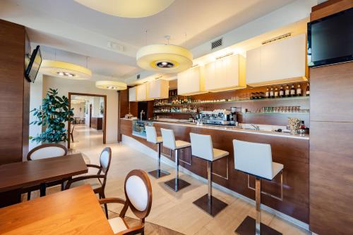 a restaurant with a bar with white chairs and tables at Il Gentiluomo Hotel & SPA in Arezzo