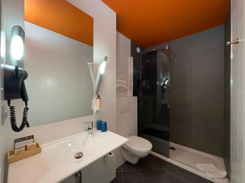 a bathroom with a sink and a toilet and a phone at The Originals Boutique, Hôtel de la Paix, Brest in Brest