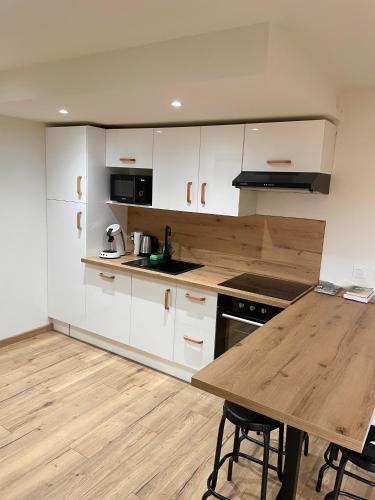 une cuisine avec des armoires blanches et une table en bois dans l'établissement Appartement Charmant T2, à Banyuls-sur-Mer