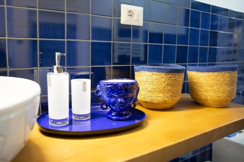 a bathroom with blue tiled walls and a counter with two bottles and a toilet at Le Due Sorelle in Vietri sul Mare