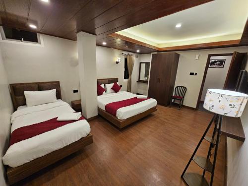 a hotel room with two beds and a lamp at Hotel Tara Palace Darjeeling in Darjeeling