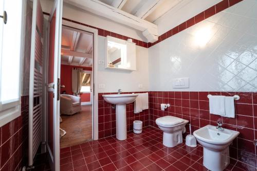 a red tiled bathroom with a sink and a toilet at Foresteria San Rocco Borgoluce in Susegana