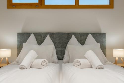a white bed with white pillows and two lamps at Stadtapartments Luna by Cosy Homes in Villach