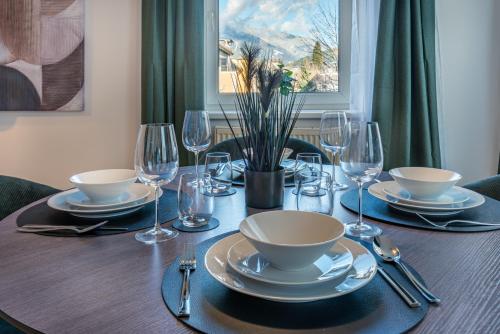a wooden table with plates and wine glasses on it at Stadtapartments Luna by Cosy Homes in Villach