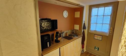 une cuisine avec un évier et une horloge murale dans l'établissement Evasion Bourguignonne, à Montchanin