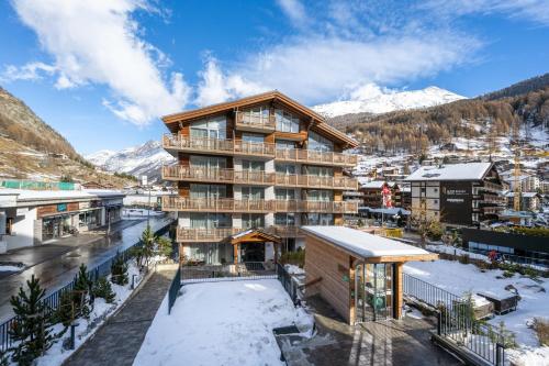 un edificio de apartamentos en las montañas con nieve en Naco Aparthotel by Arca Spa, en Zermatt