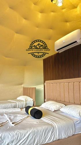 two beds in a room with a sign on the wall at Grand luxury rum in Wadi Rum