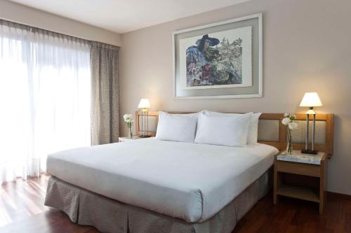 a bedroom with a large white bed and a window at NH Córdoba Urbano in Córdoba