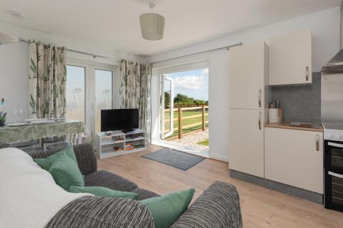 a living room with a couch and a tv and a kitchen at Farmhouse Apartment with Paddock & Orchard Views in Woodnesborough