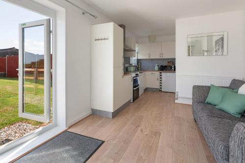 a living room with a couch and a kitchen at Farmhouse Apartment with Paddock & Orchard Views in Woodnesborough
