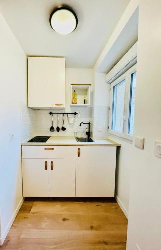 une cuisine avec des armoires blanches et un évier dans l'établissement Cosy apartment City Center, à Montlhéry