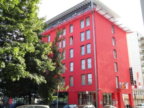 a red building with cars parked in front of it at Grand Hotel Dream Main City Center in Frankfurt