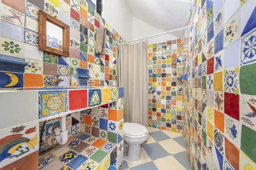 a bathroom with a toilet and a bunch of tiles at Casa Amigos in Isla Mujeres