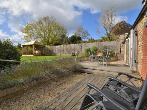 a house with a deck with a table and a gazebo at Mallows Byre Yetminster in Sherborne