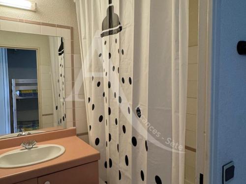 une salle de bain avec un lavabo et un rideau de douche dans l'établissement rez de jardin residence en bord de mer piscine tennis stationnement, à Sète