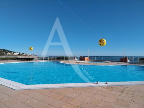 une grande piscine bleue avec deux balles dans l'air dans l'établissement rez de jardin residence en bord de mer piscine tennis stationnement, à Sète