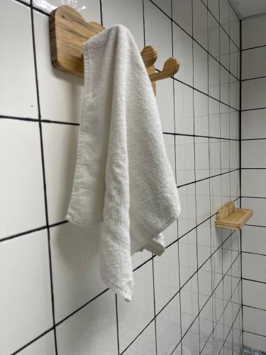 a white towel hanging on a wall in a bathroom at Grand'Hostel in São Cristóvão