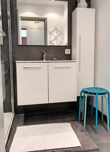 La salle de bains est pourvue d'un lavabo et d'un tabouret bleu. dans l'établissement Bord de mer, terrasse vue mer 228L, à Cannes
