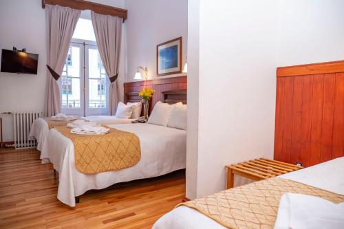 a hotel room with two beds and a window at Hotel Plaza in Punta Arenas