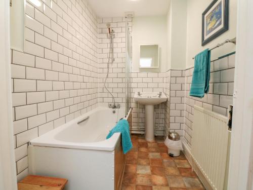 a white bathroom with a tub and a sink at The Well House Apartment in Watchet