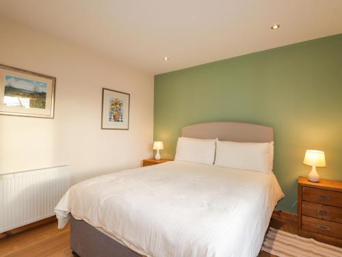 a bedroom with a large white bed with two lamps at Bruach Gorm Cottage in Grantown on Spey