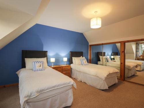a bedroom with two beds and a blue wall at Bruach Gorm Cottage in Grantown on Spey