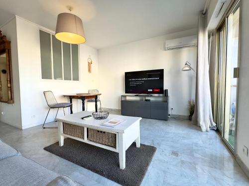 un salon avec un canapé, une table et une télévision dans l'établissement L'Alexandra By SCLS Locations, à Cannes