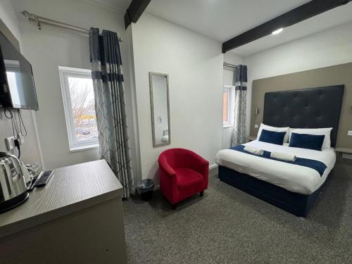 a bedroom with a bed and a red chair at Abbey Hotel in Leicester
