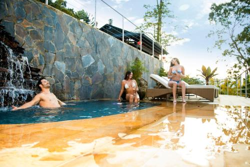 a group of people sitting in a swimming pool with a waterfall at GreenOriental Resort in La Vega