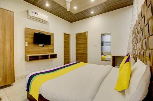 a bedroom with a large bed with a tv on the wall at Black Diamond Hotel & Spa in Zirakpur