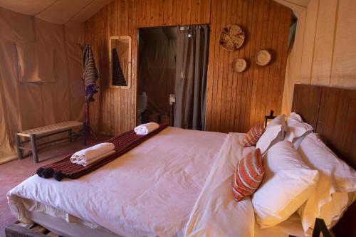 a bedroom with a large bed with white sheets and pillows at Erg Chigaga Torza Luxury Camp - Desert Glamping in El Gouera