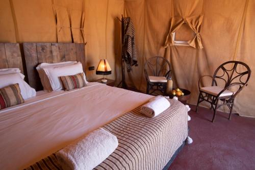 a bedroom with a large bed and two chairs at Erg Chigaga Torza Luxury Camp - Desert Glamping in El Gouera